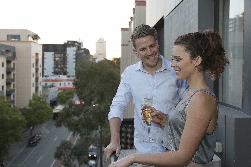 Couple having a drink on the balcony of Mont Clare Apartment.