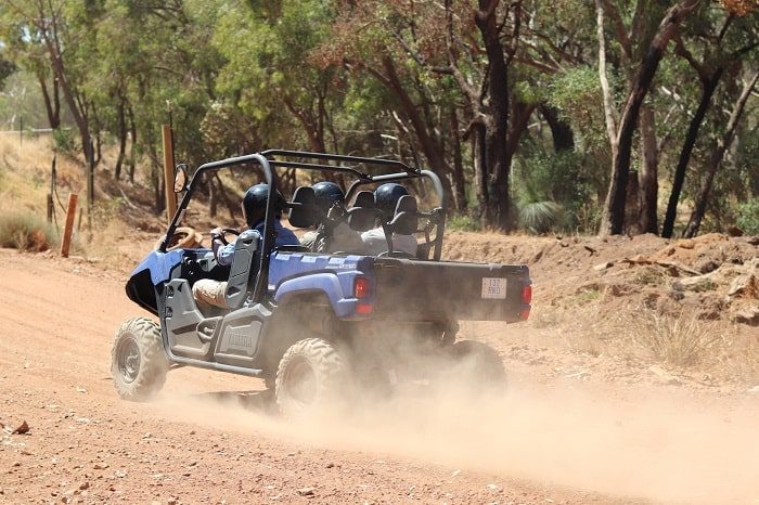 3 Men on a quad bike or side-by-side vehicle at a sand track.